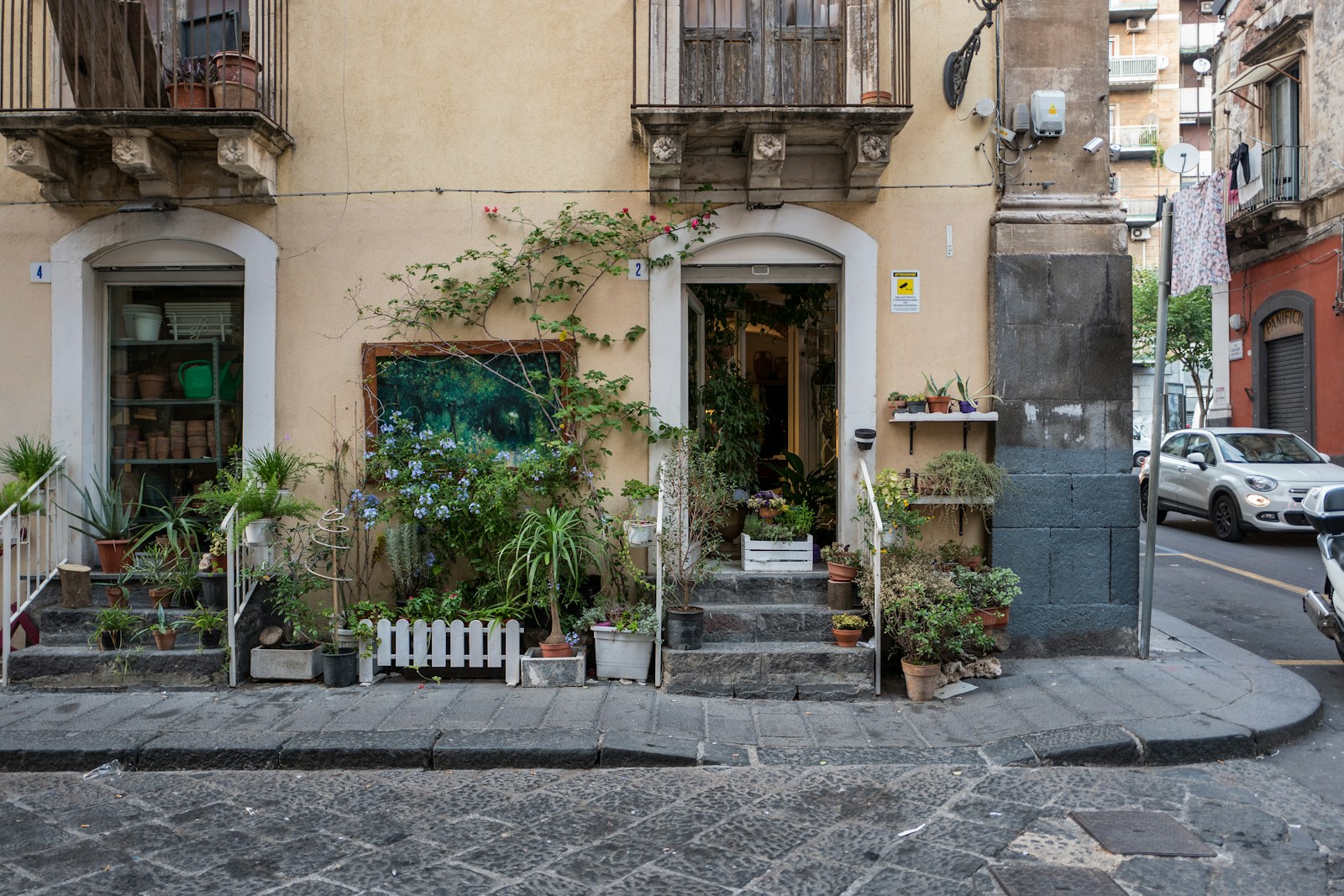 beige concrete building with flowers and plants in doorway